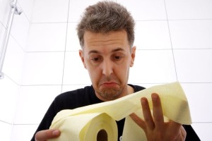 A depressed man with IBS symptoms looking at toilet paper