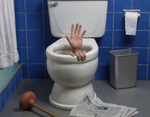 Hand reaches up through the seat from out of a toilet in a domestic bathroom.