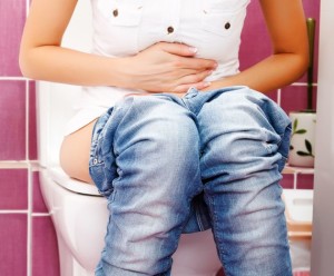 Woman with belly pains, sitting on the toilet.