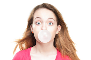 Wide eyed woman blowing a bubble with chewing gum.