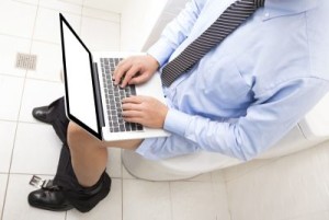 Business man working on the toilet with a laptop.